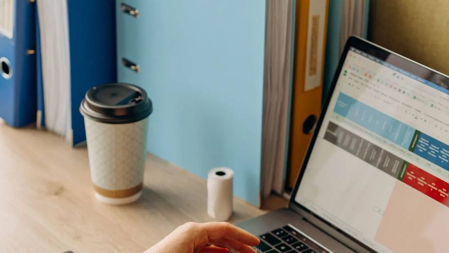 A spreadsheet open on a laptop next to a coffee