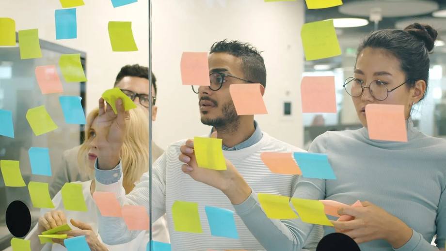 A product team planning work with notes on a glass wall