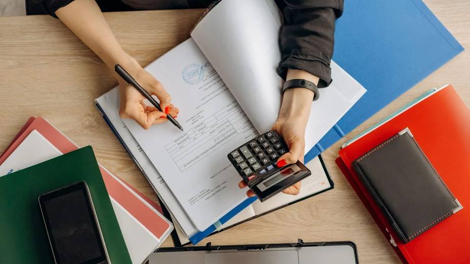 Bookkeeping papers, a calculator and folders on a desk
